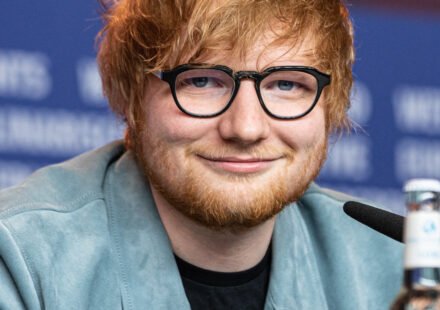 Ed Sheeran performing on stage with a guitar during a live concert