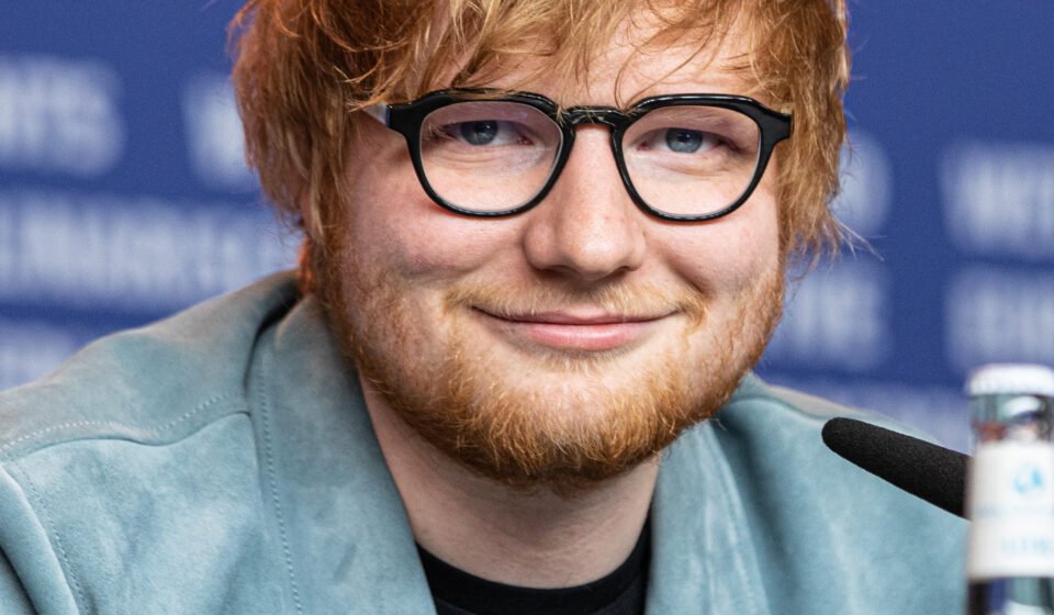 Ed Sheeran performing on stage with a guitar during a live concert